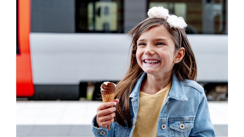 Glad flicka äter glass framför ett Öresundståg.