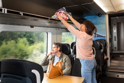 Passagerare lägger väska på hatthyllan. Foto: Apelöga/Öresundståg