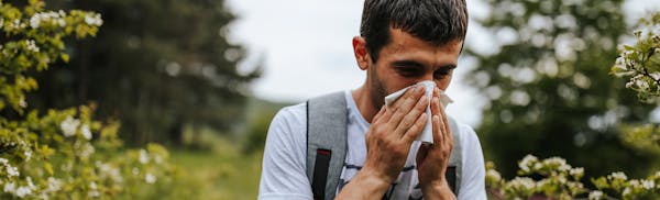 man sneezing into tissue