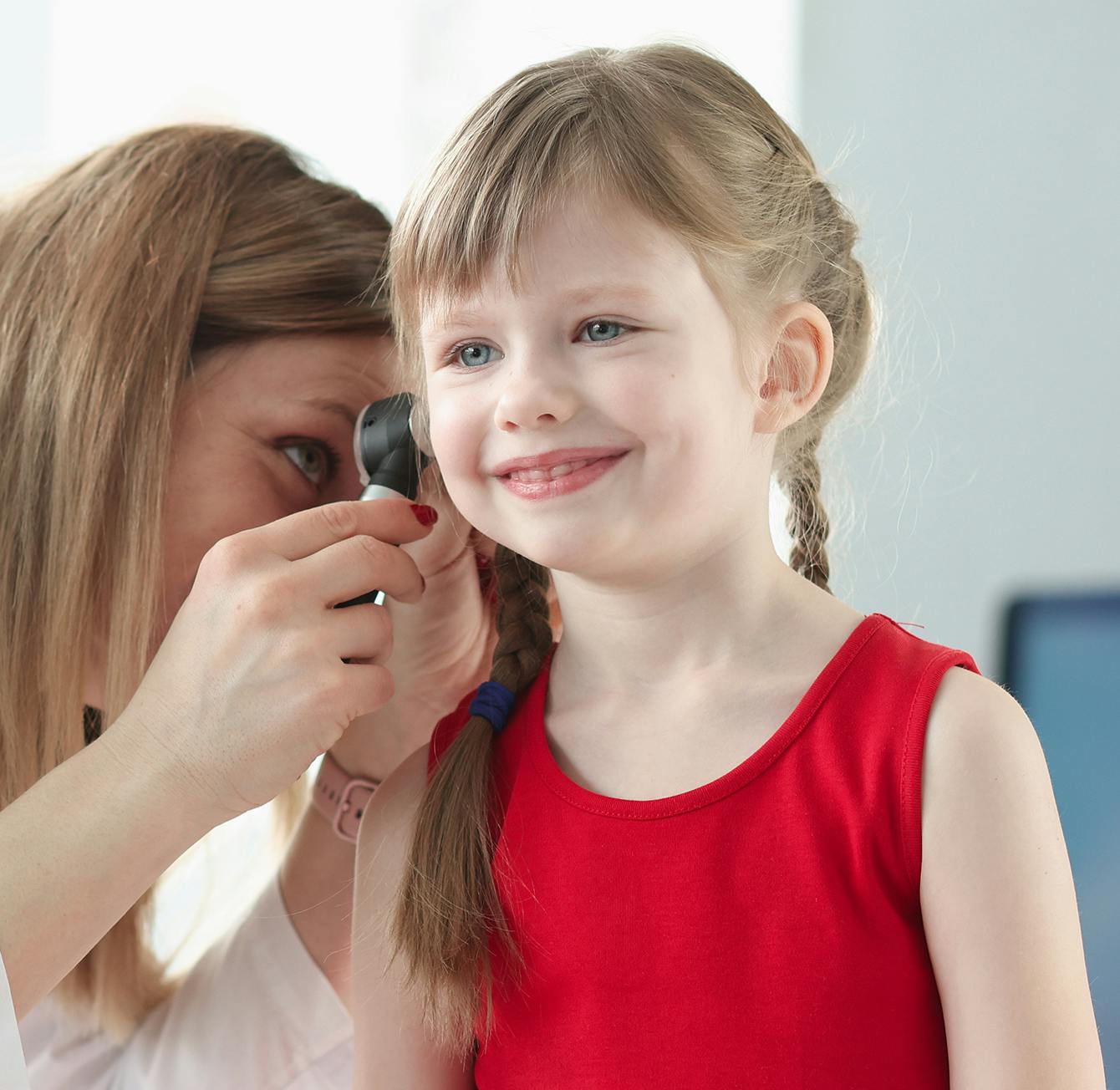 woman inspecting a little girls ear