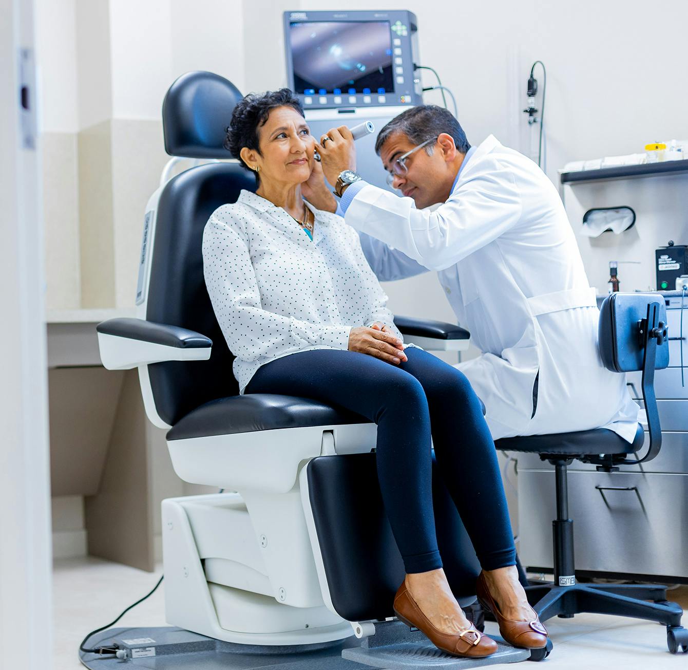 there is a woman that is sitting getting ear inspected