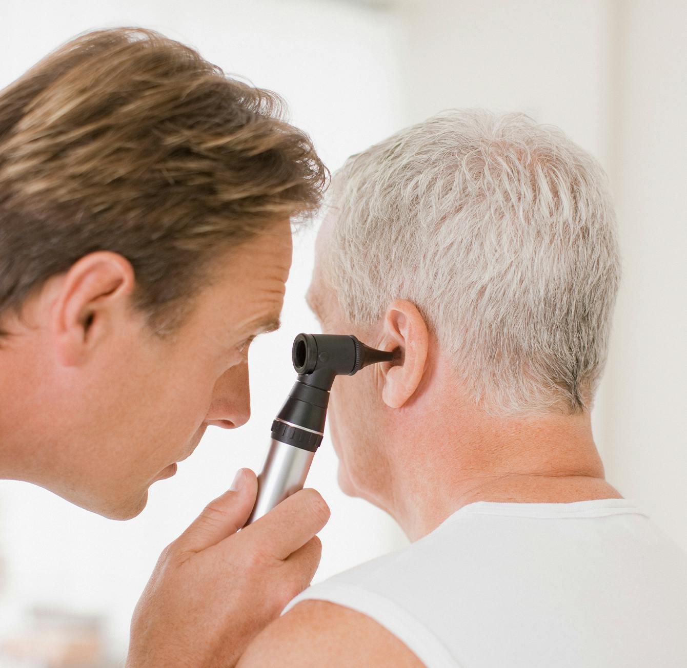 there is a man getting an ear exam from a doctor