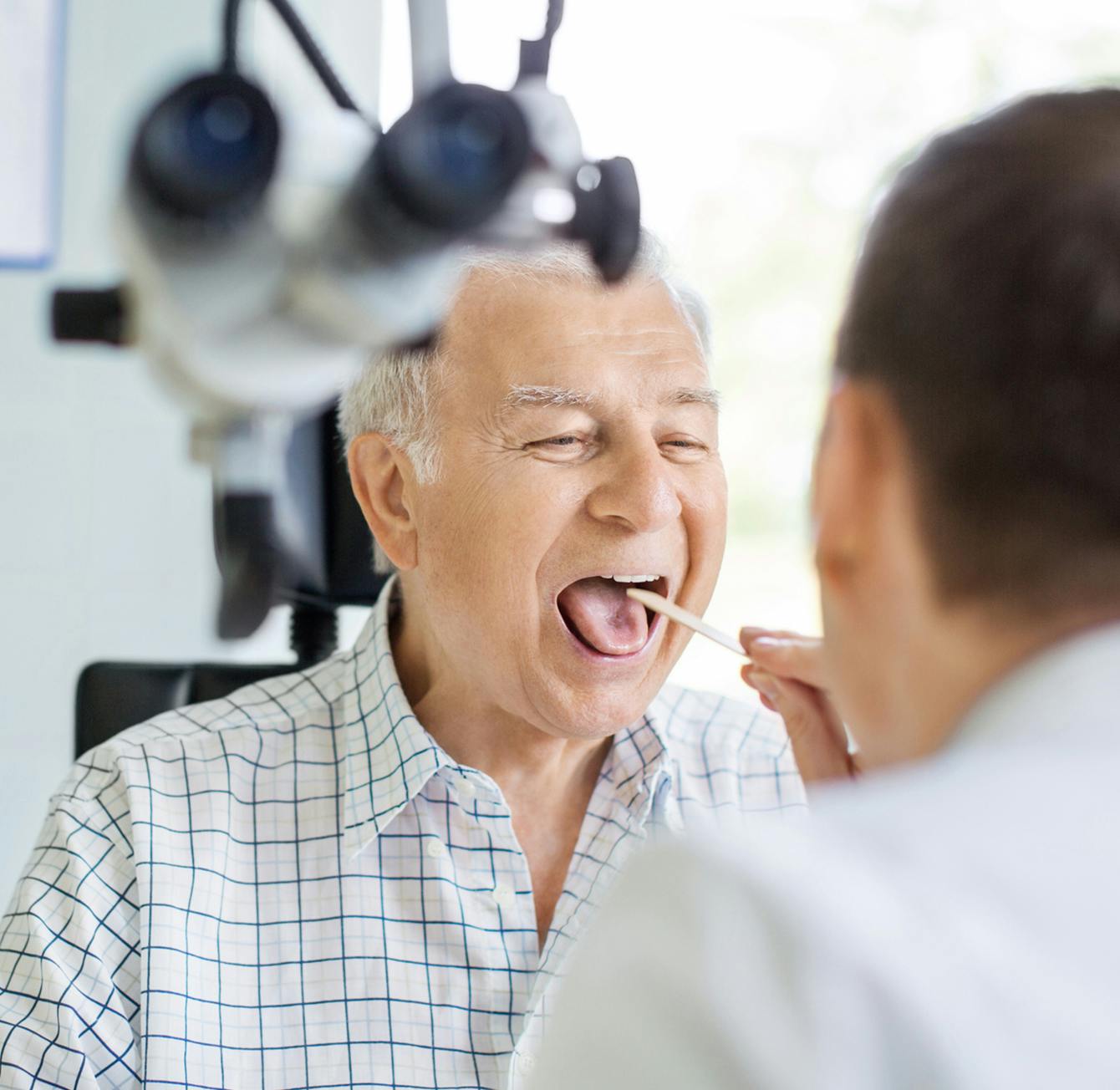 there is a man getting his mouth inspected by a doctor