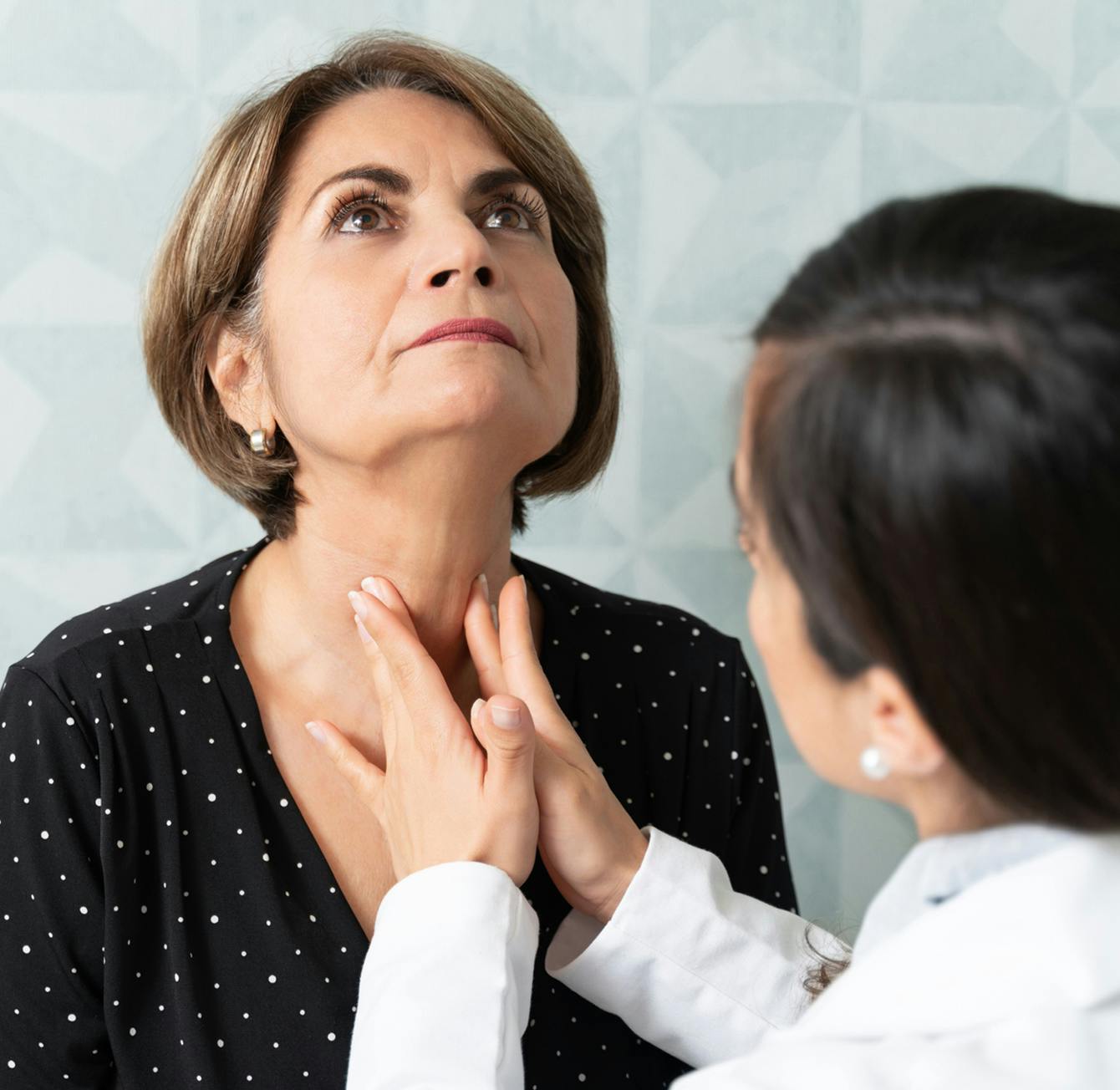 there is a woman that is getting her throat examined by a doctor