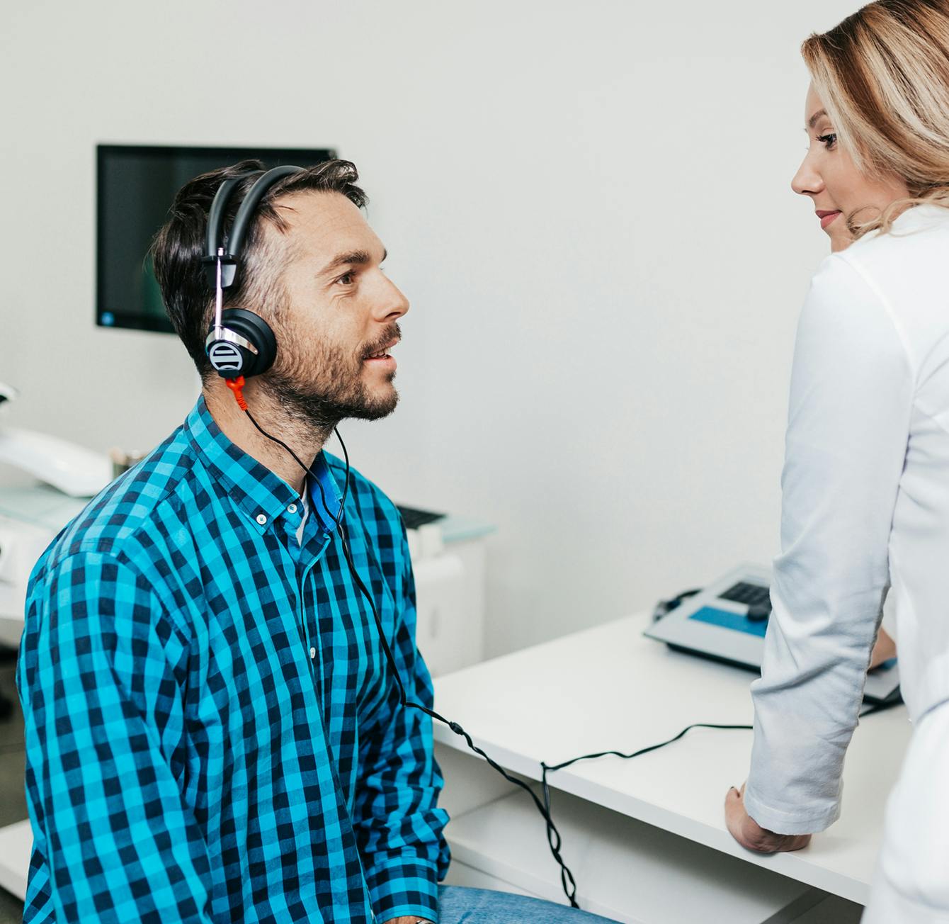 there is a man sitting at a desk with a computer and headphones on