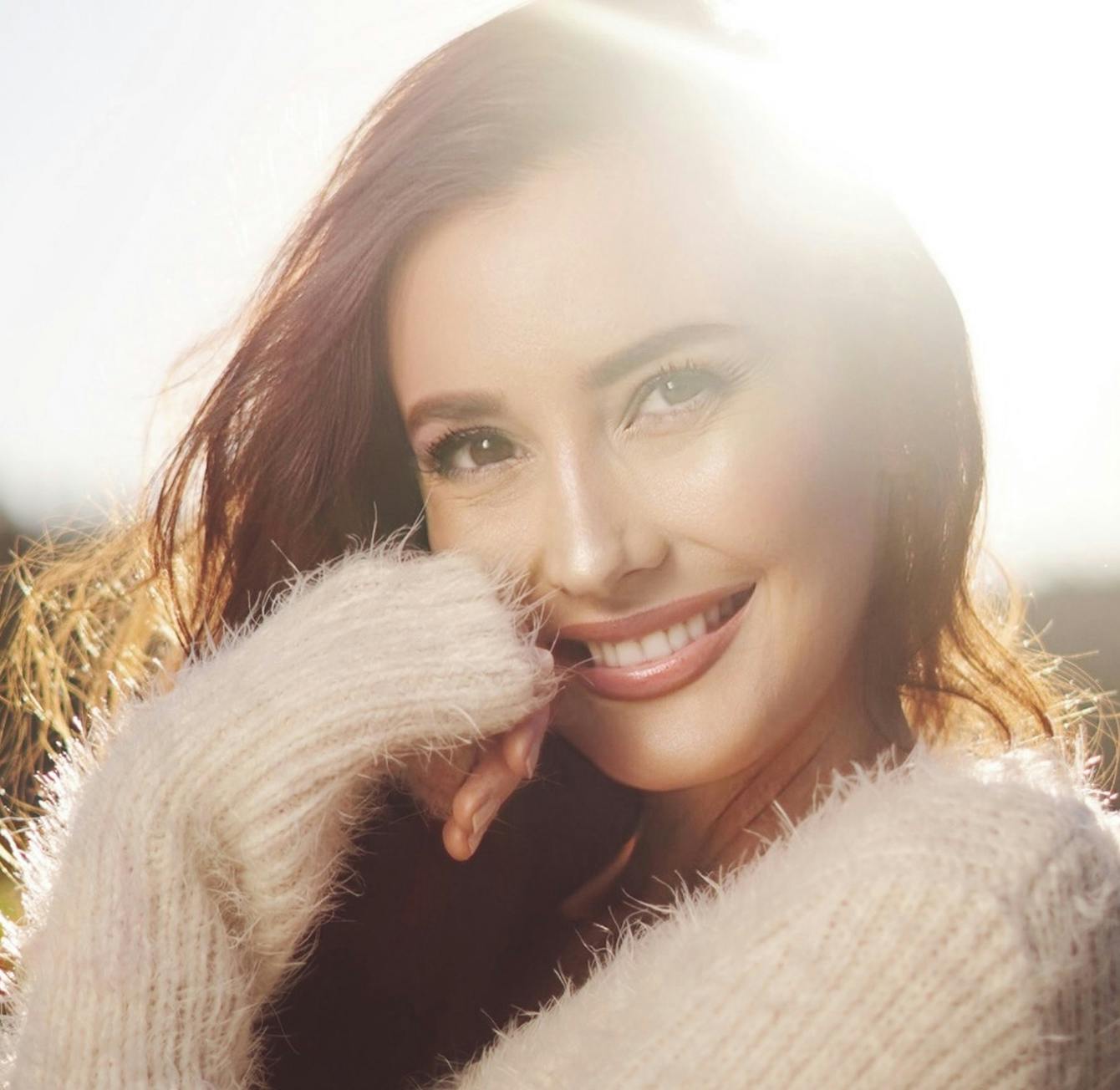 smiling woman in a white sweater posing for a picture