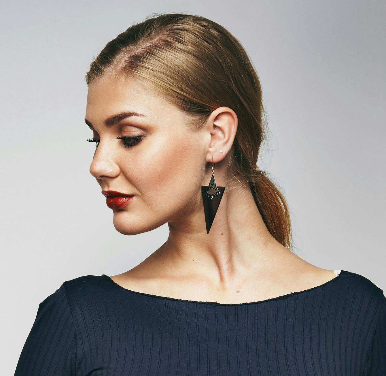 woman with a ponytail and earrings wearing a black dress