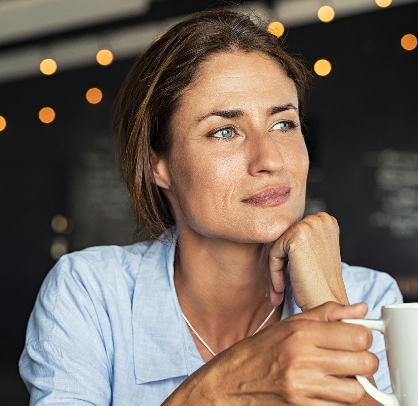 there is a woman sitting at a table with a cup of coffee