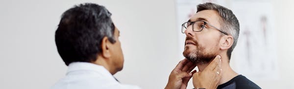 there is a man getting his neck examined by a doctor