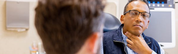 there is a man that is looking at his neck in the mirror