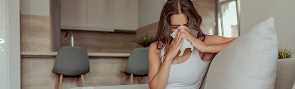 Women On Her Couch Blowing Her Nose