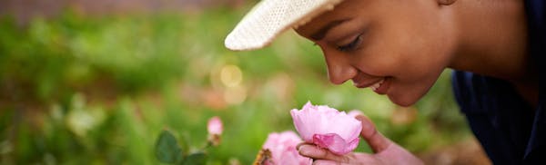 there is a woman that is smelling a flower in the grass