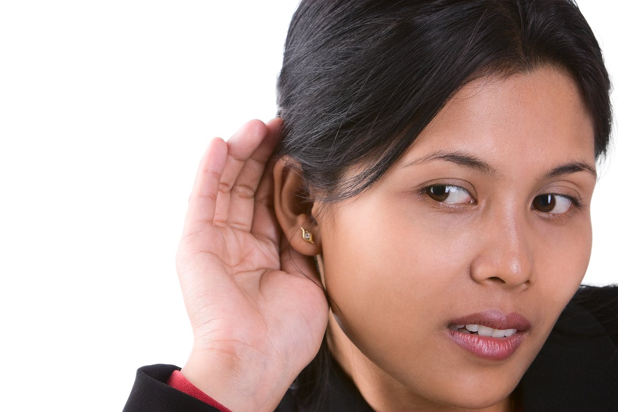 Woman cupping her ear trying to hear something.