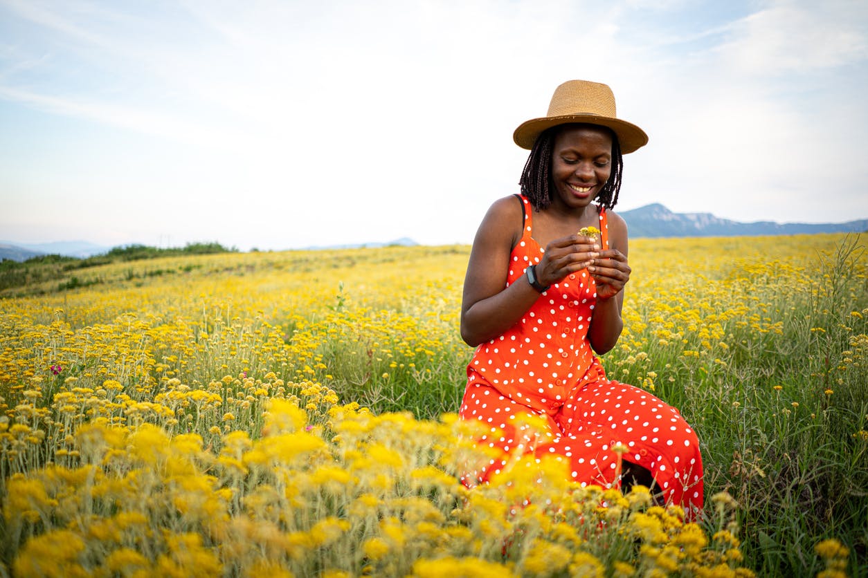 Woman with a hat and dress standing in a field of flowers