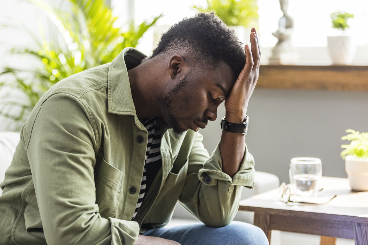 Man sitting with his palm to his forehead