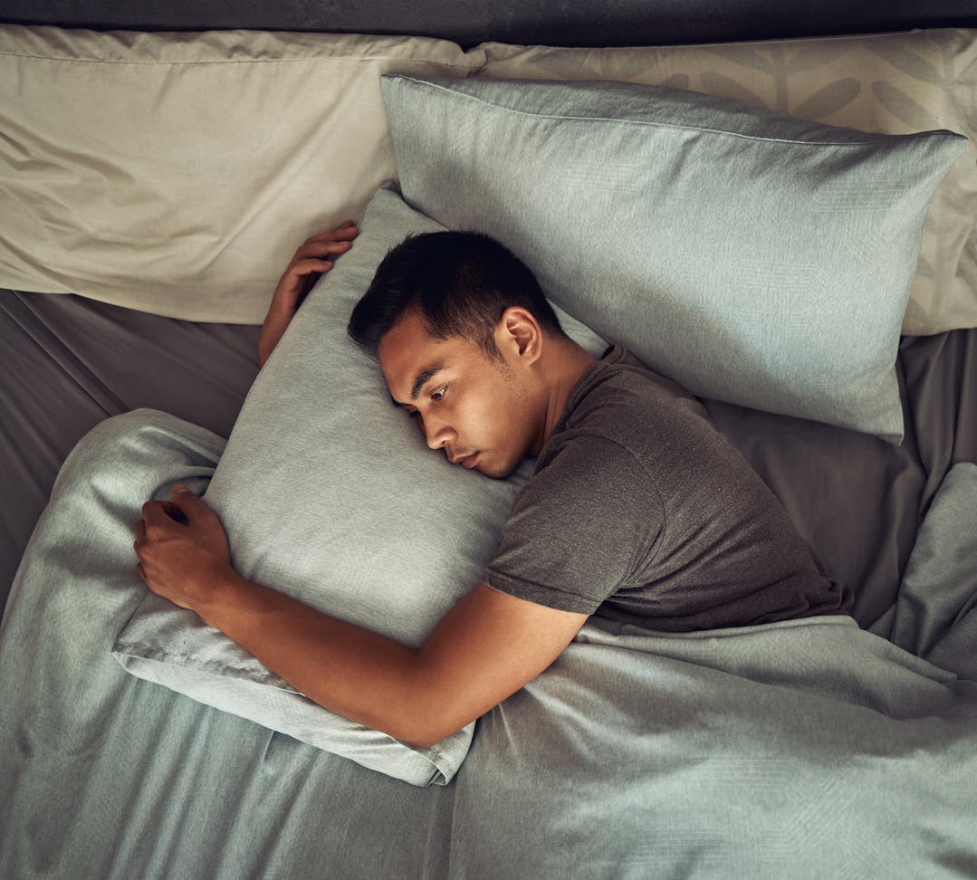 Top view of a man lying in bed with his eyes open