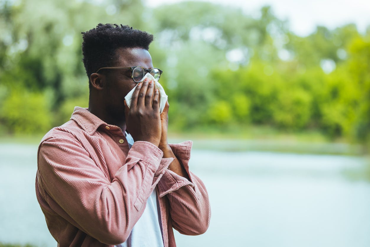 African American man blowing his nose while outside