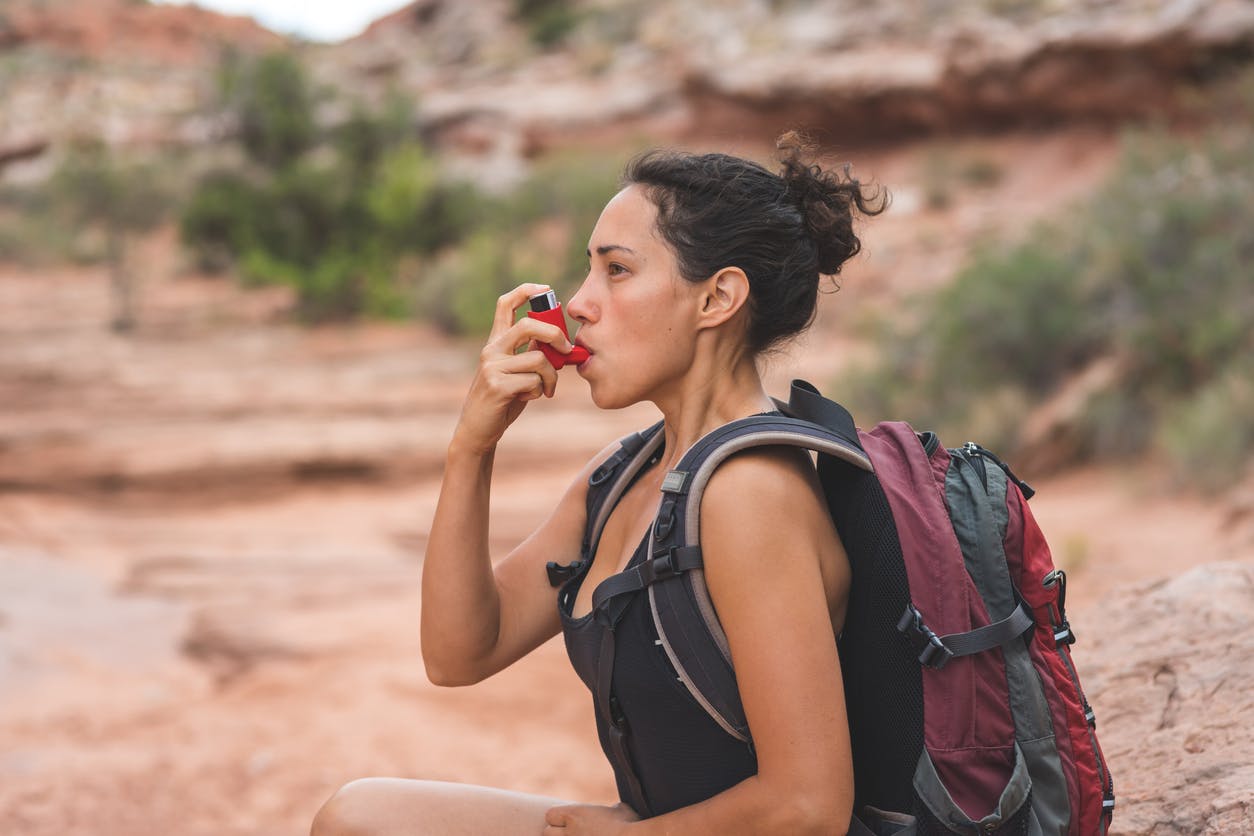 Woman on a hike stopping to use her inhaler