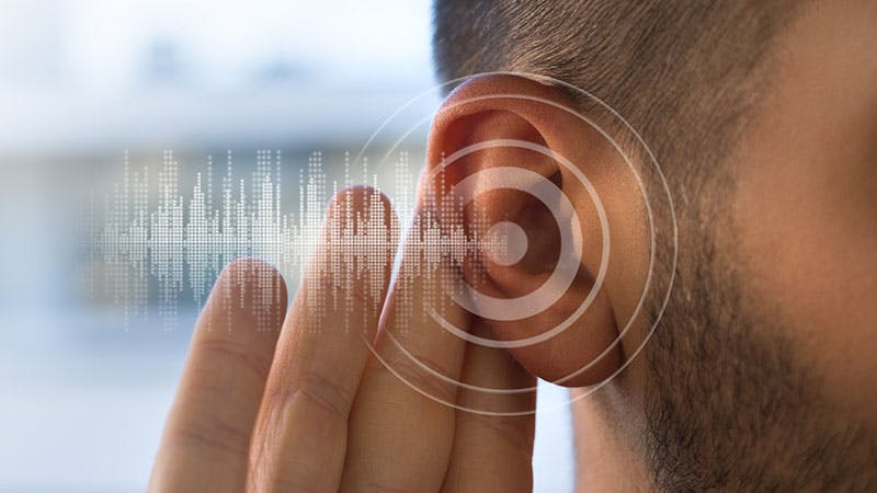 a close up of a man with a ear in front of a computer screen