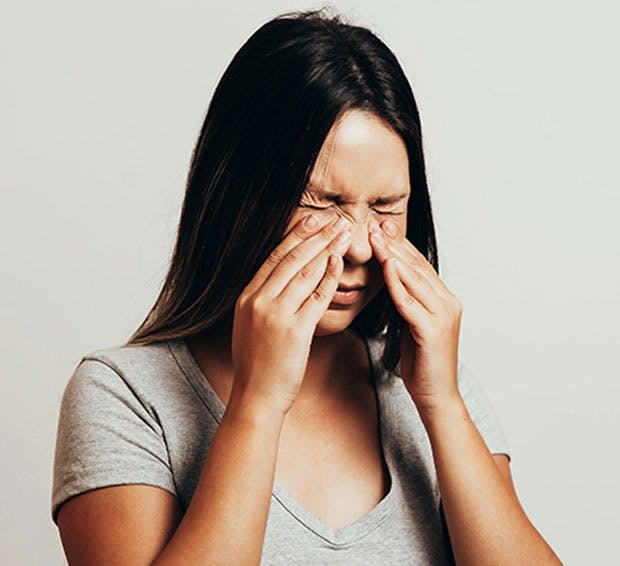 Woman holding her nose in pain