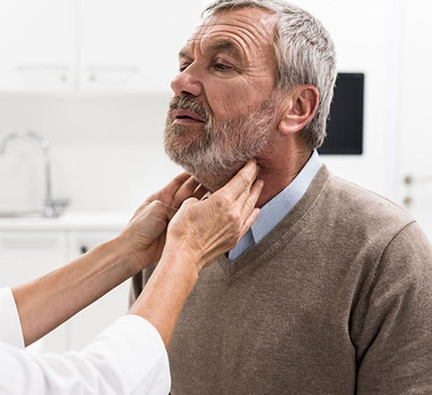 doctor examining a man's neck with a stethoscope