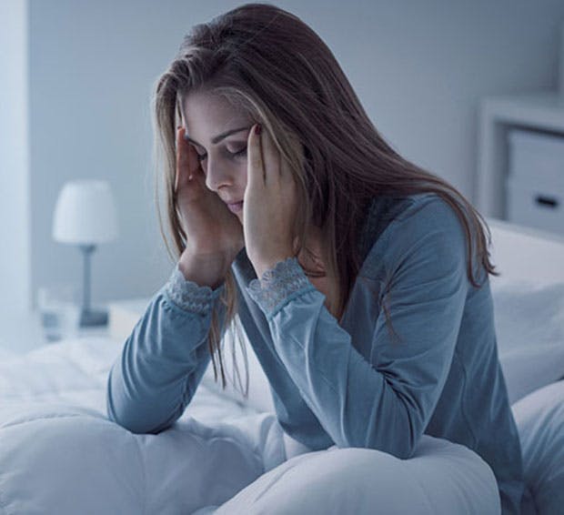 woman sitting on a bed with her head in her hands