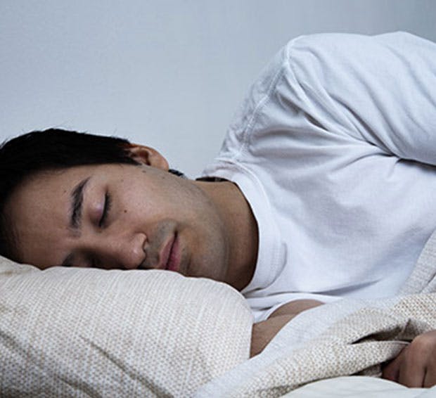 there is a man sleeping in bed with a white blanket