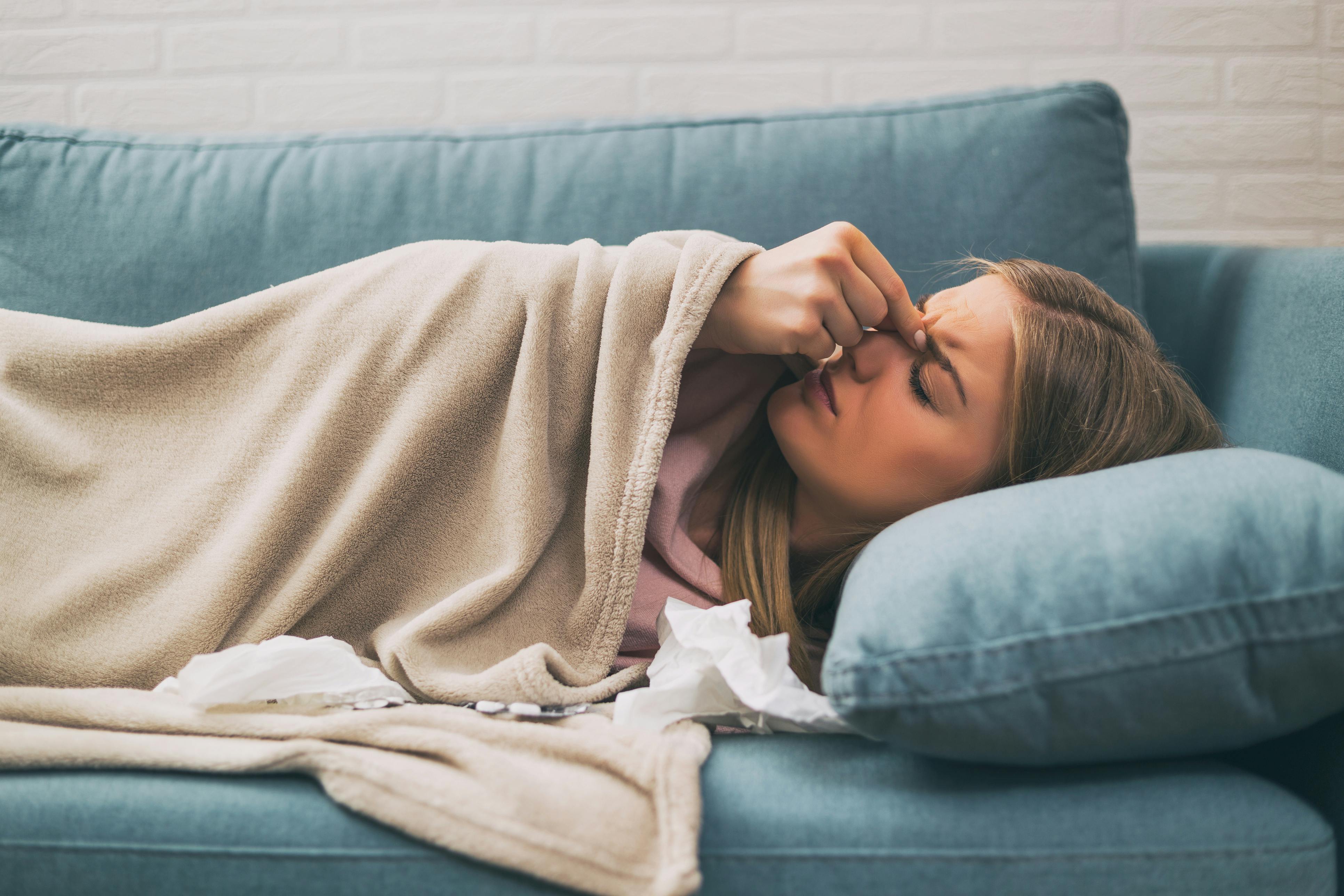 Woman lying on the couch pinching her nose