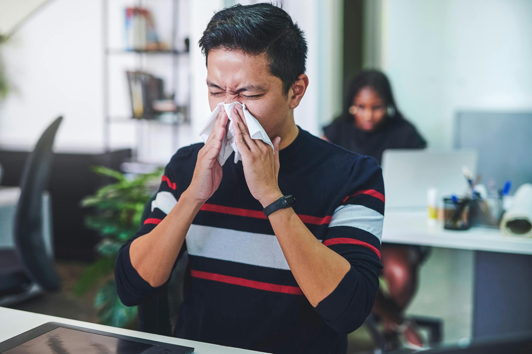 Man blowing his nose at work