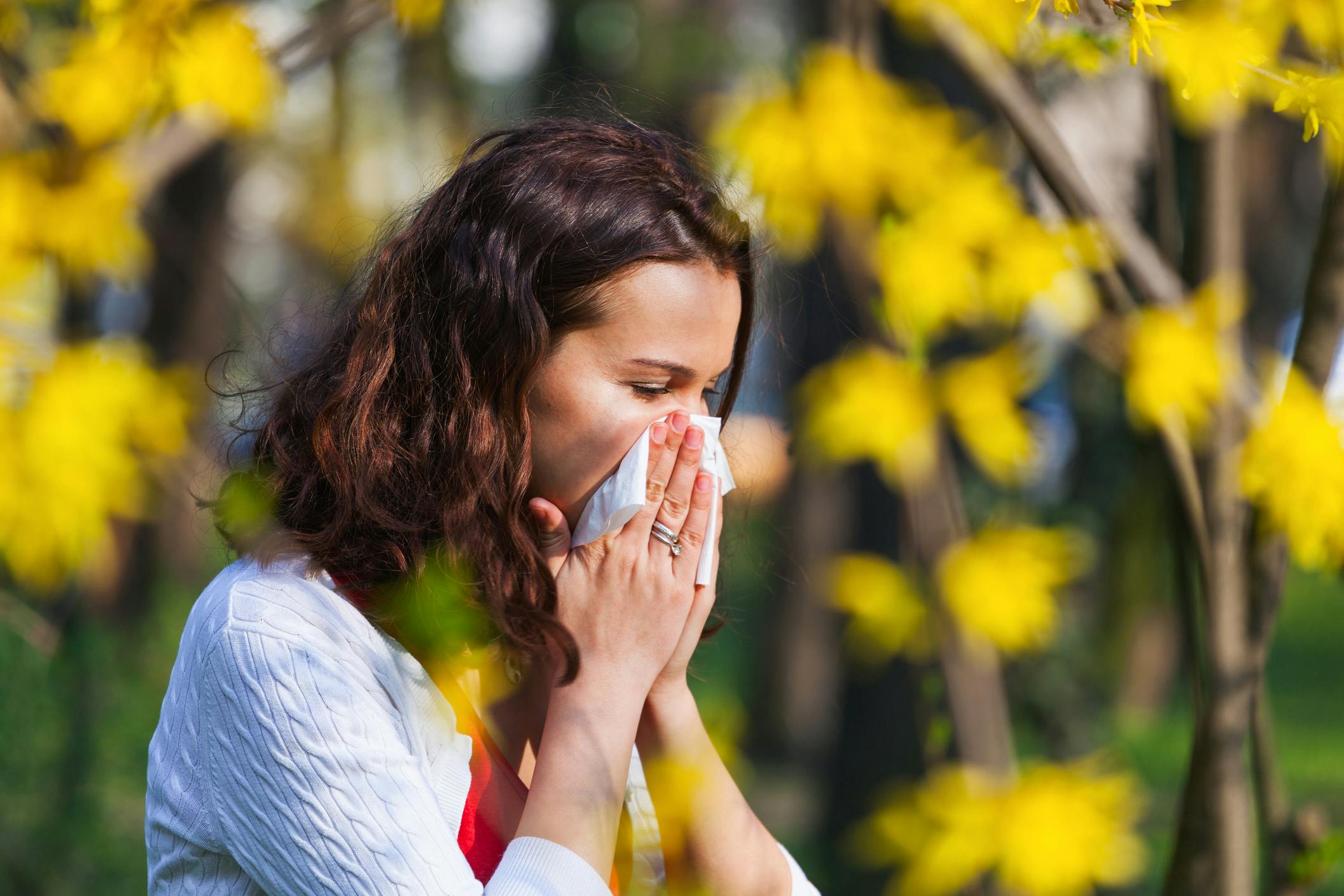 woman blowing nose near flowers