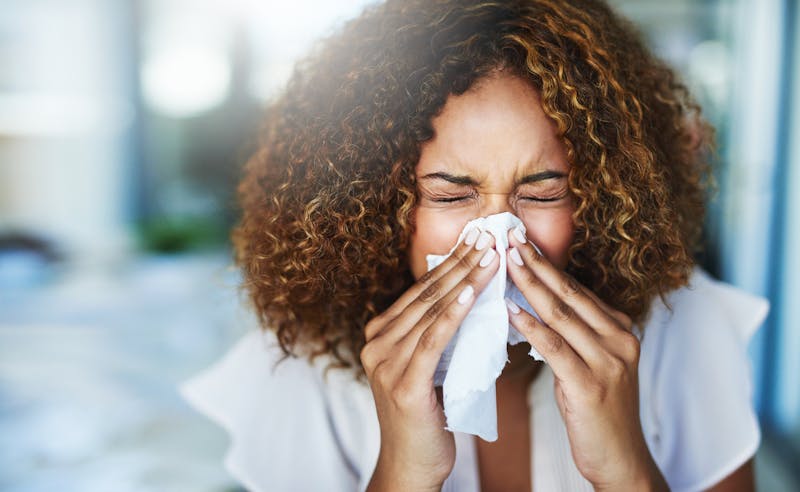woman sneezing into tissue