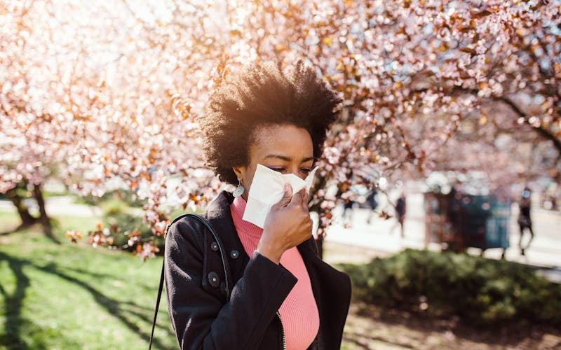 woman sneezing into tissue