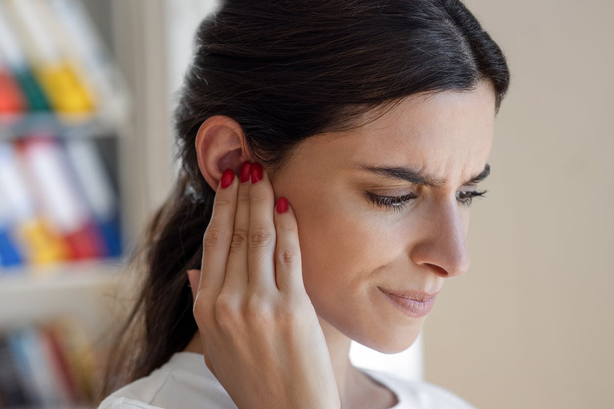 woman holding her ear