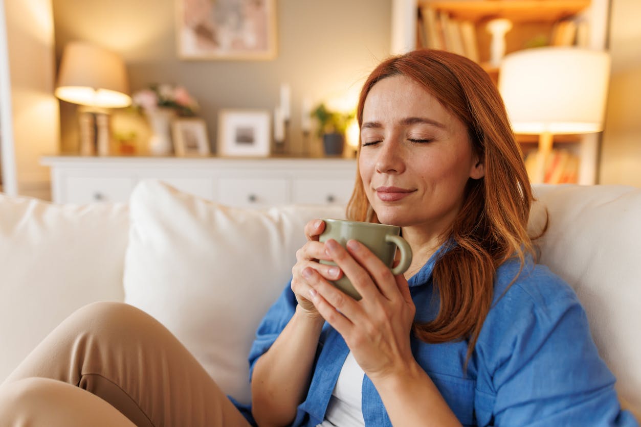 red haired woman smelling coffee