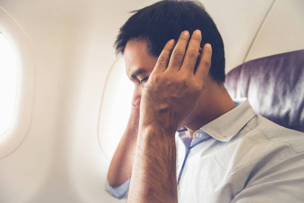 Man with an ear ache on a plane