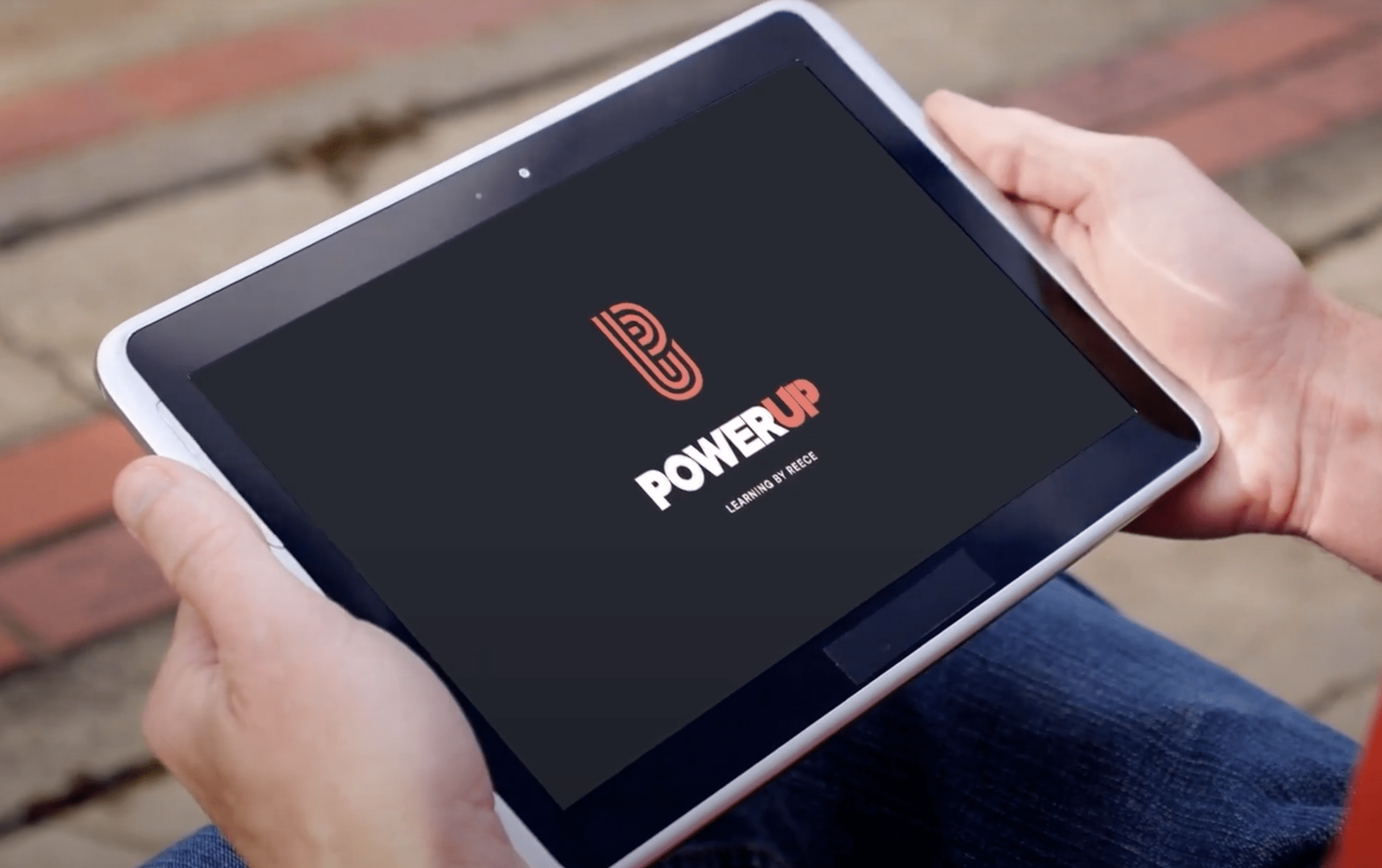 Hands holding a tablet with PowereUp logo displayed on screen