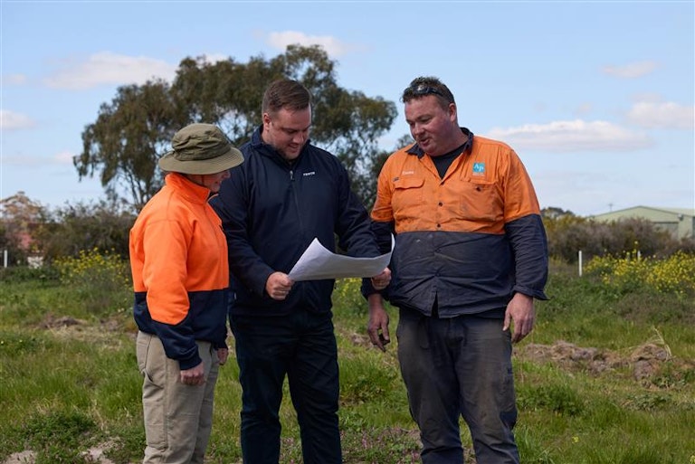Three men looking at a plan