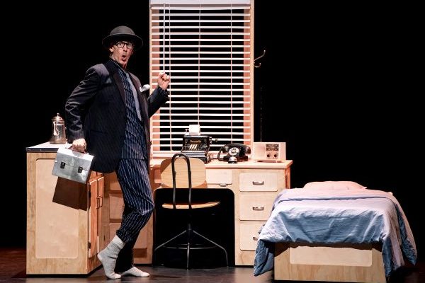 Illustrer une scène de la pièce Walter Ego où on voit homme vêtu d'un complet noir et d'un chapeau melon marchant sur une scène de spectacle 