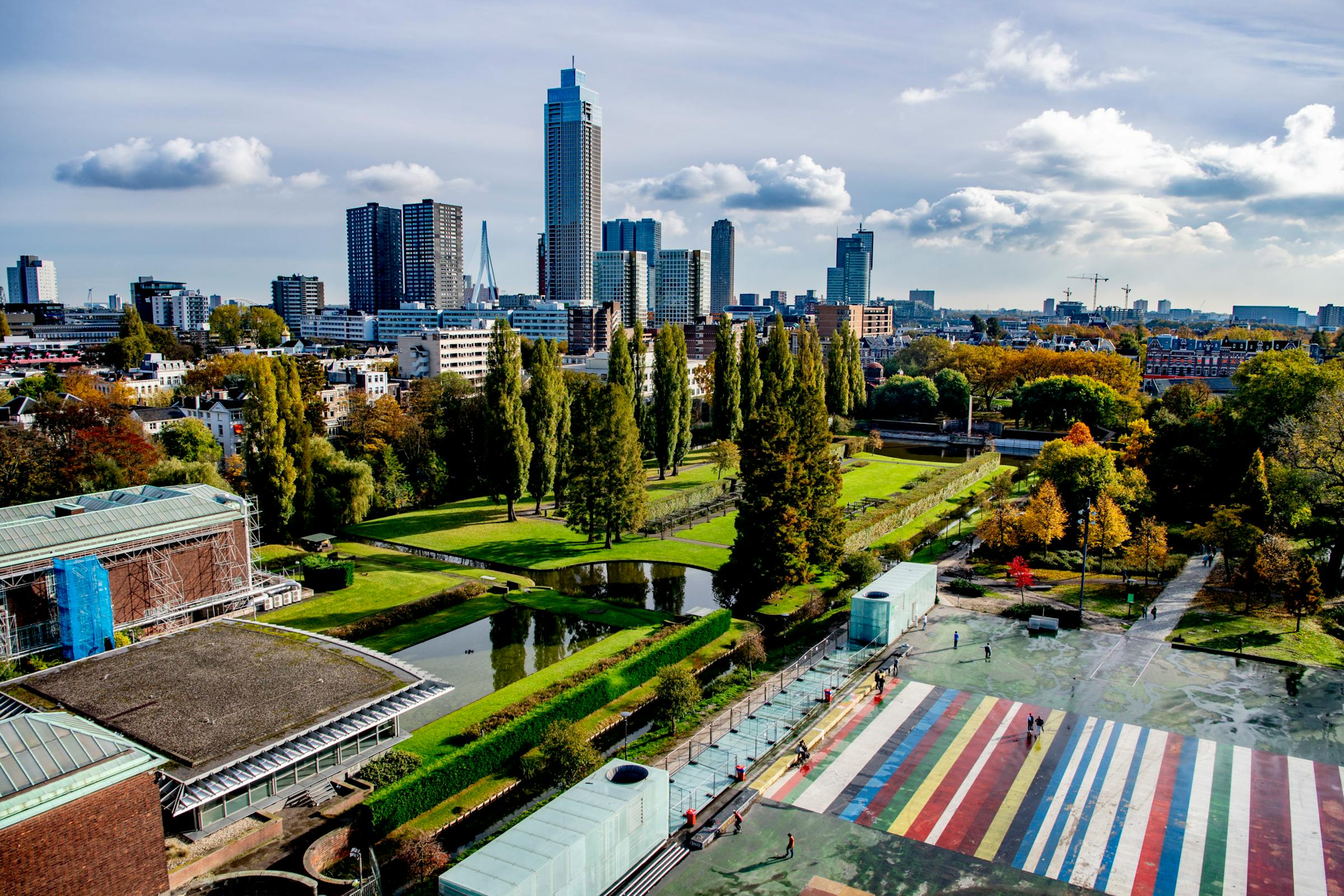 Rotterdam's skyline with the Maastoren tower rises beyond Museumpark's green lawns and canal.