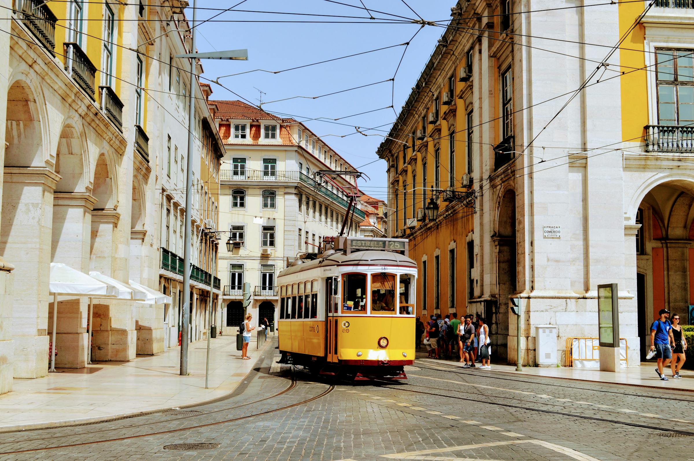 A vintage yellow tram rattles through Lisbon's cobbled streets lined with ornate façades.