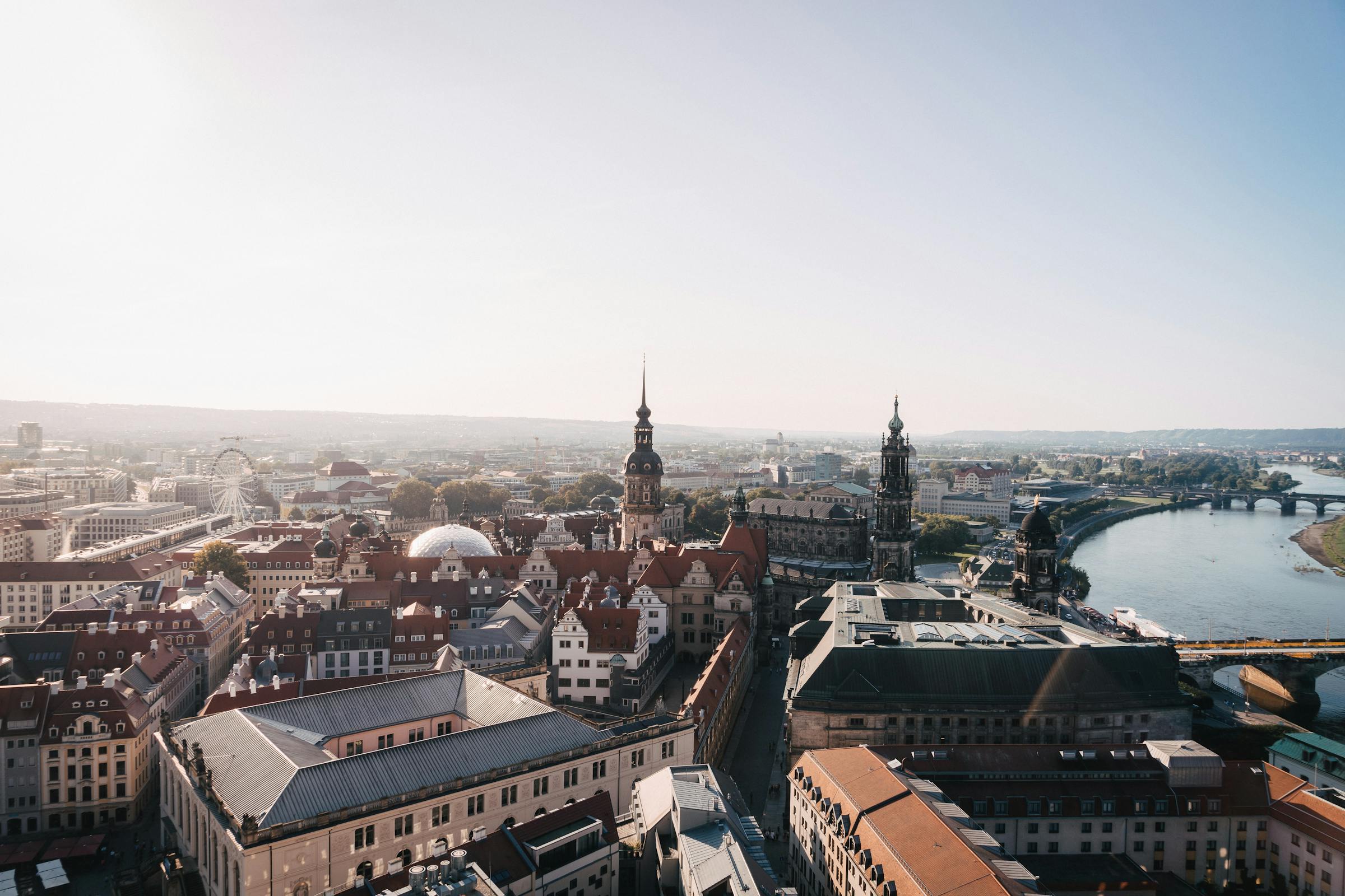 An aerial view of Dresden's Old Town skyline with domed towers, red rooftops and the River Elbe.