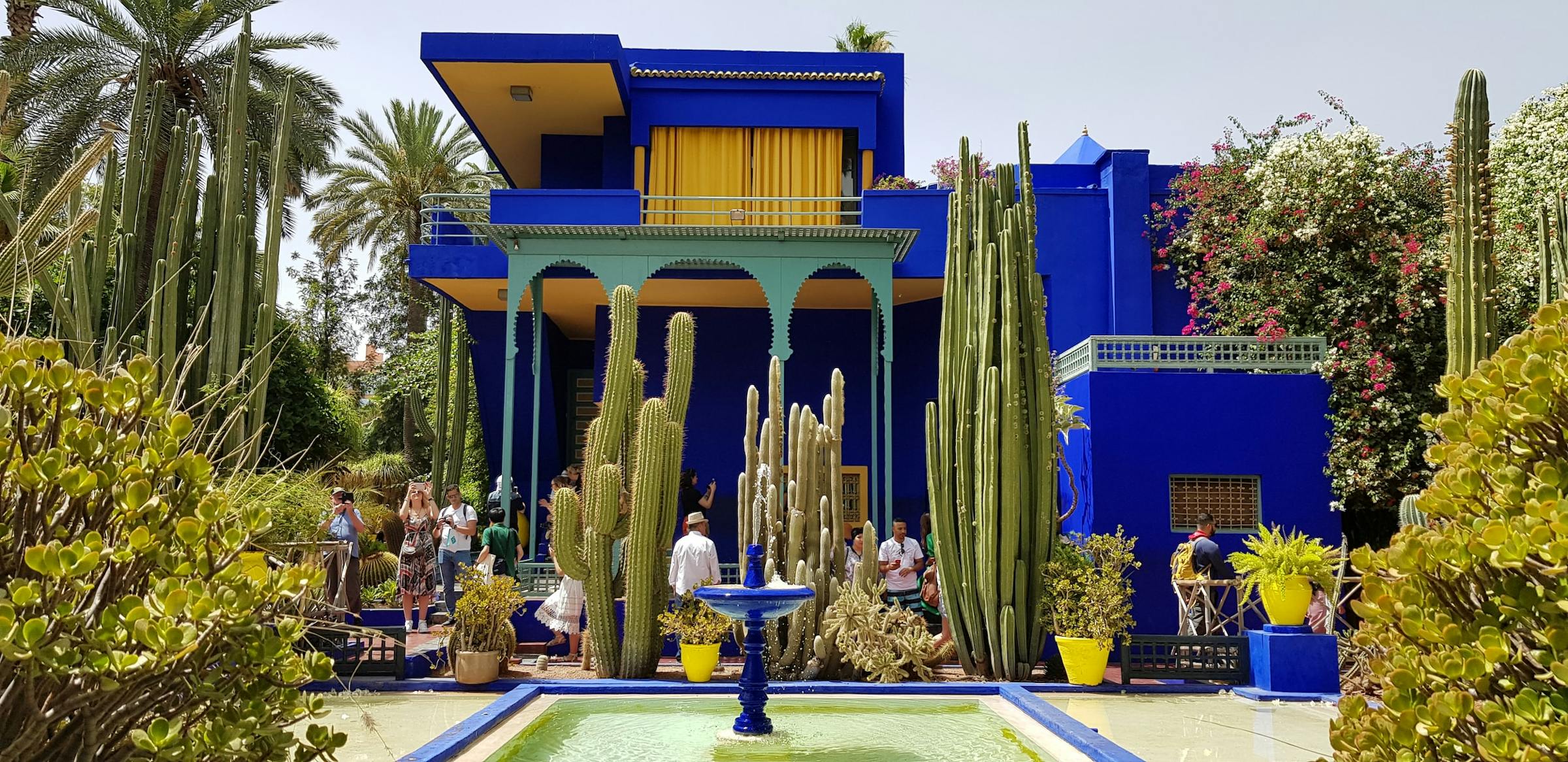 Cobalt-blue villa and tall cacti surround a fountain at the Jardin Majorelle in Marrakech.