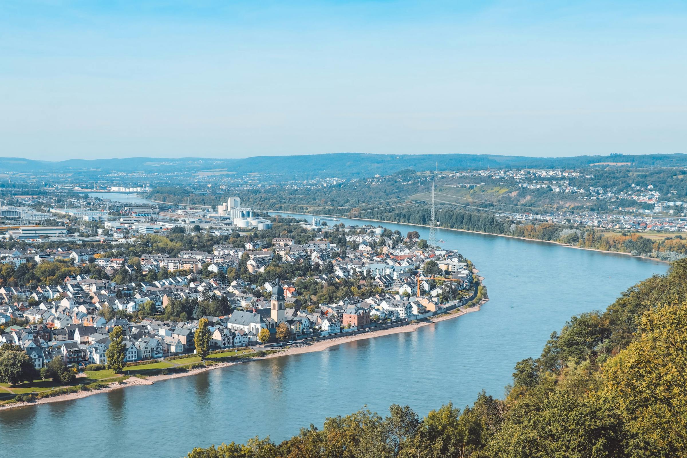 An aerial view shows Koblenz's old town curving along the Rhine, with hills beyond.