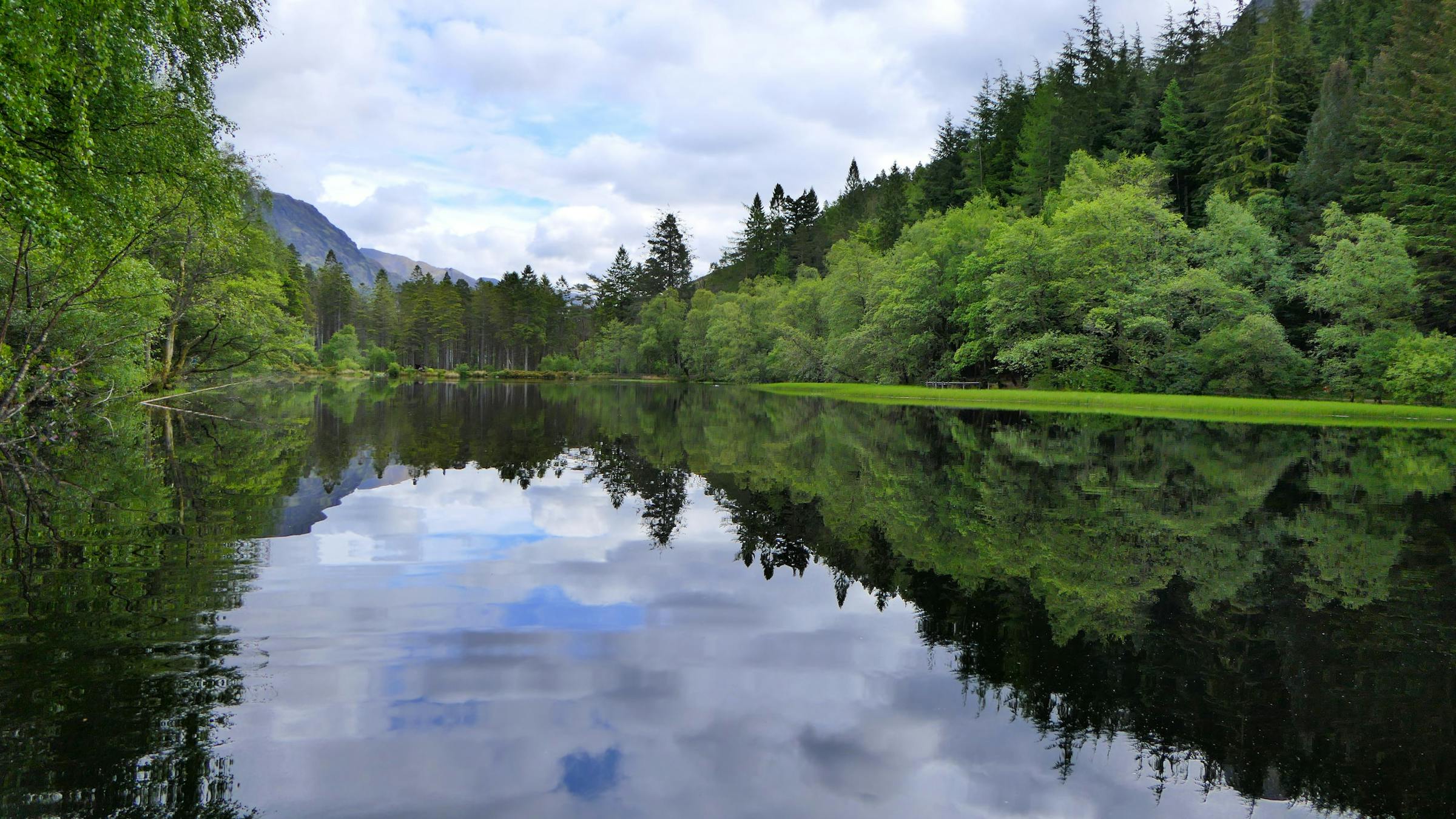 A still Highland loch mirrors surrounding forest and hills near Fort William, Scotland.