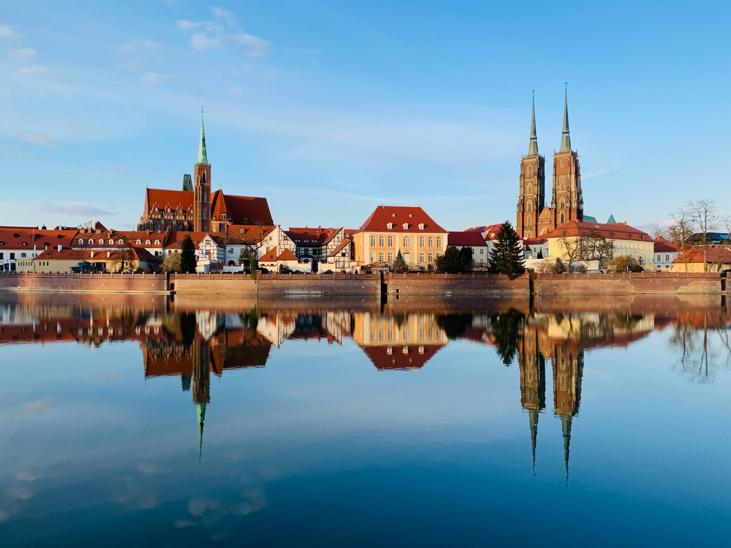 treinvakanties naar Polen uitzicht vanaf de rivier de Oder in Wrocław, Polen, op huizen met rode daken en de kathedraal op een heldere dag
