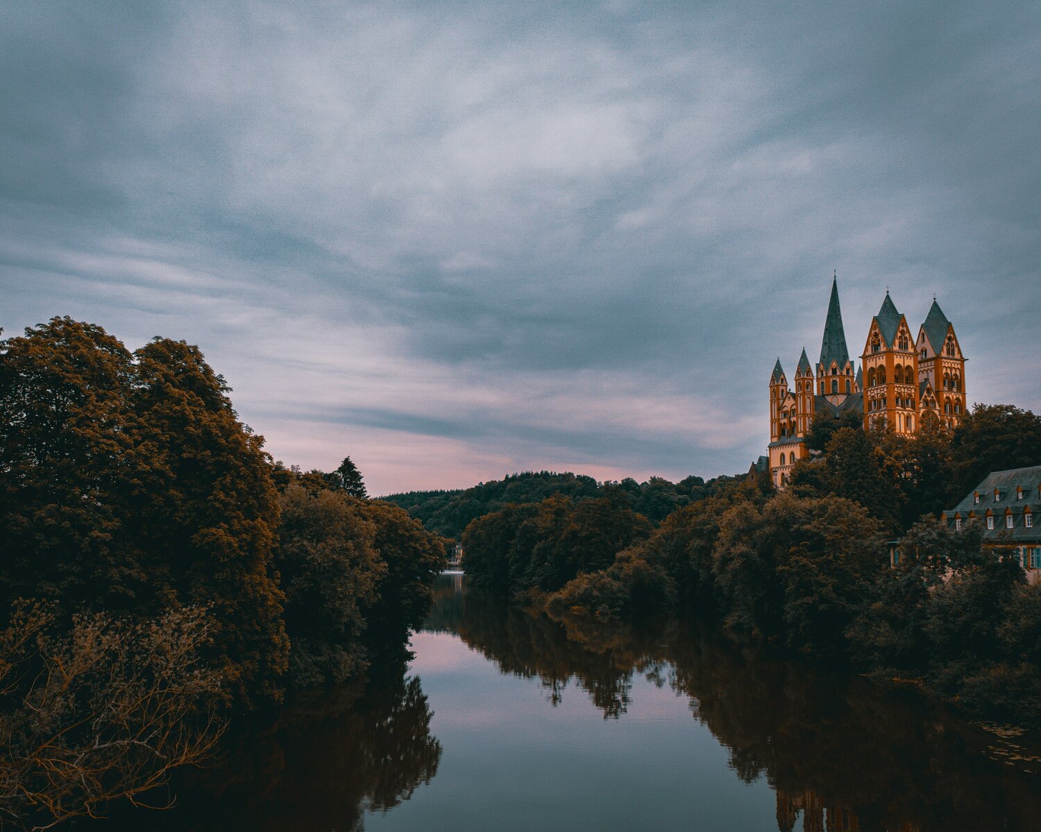 germany train holidays a view of the river Rhine in Germany with trees on each side, and a lit up castle with 5 turrets in the background