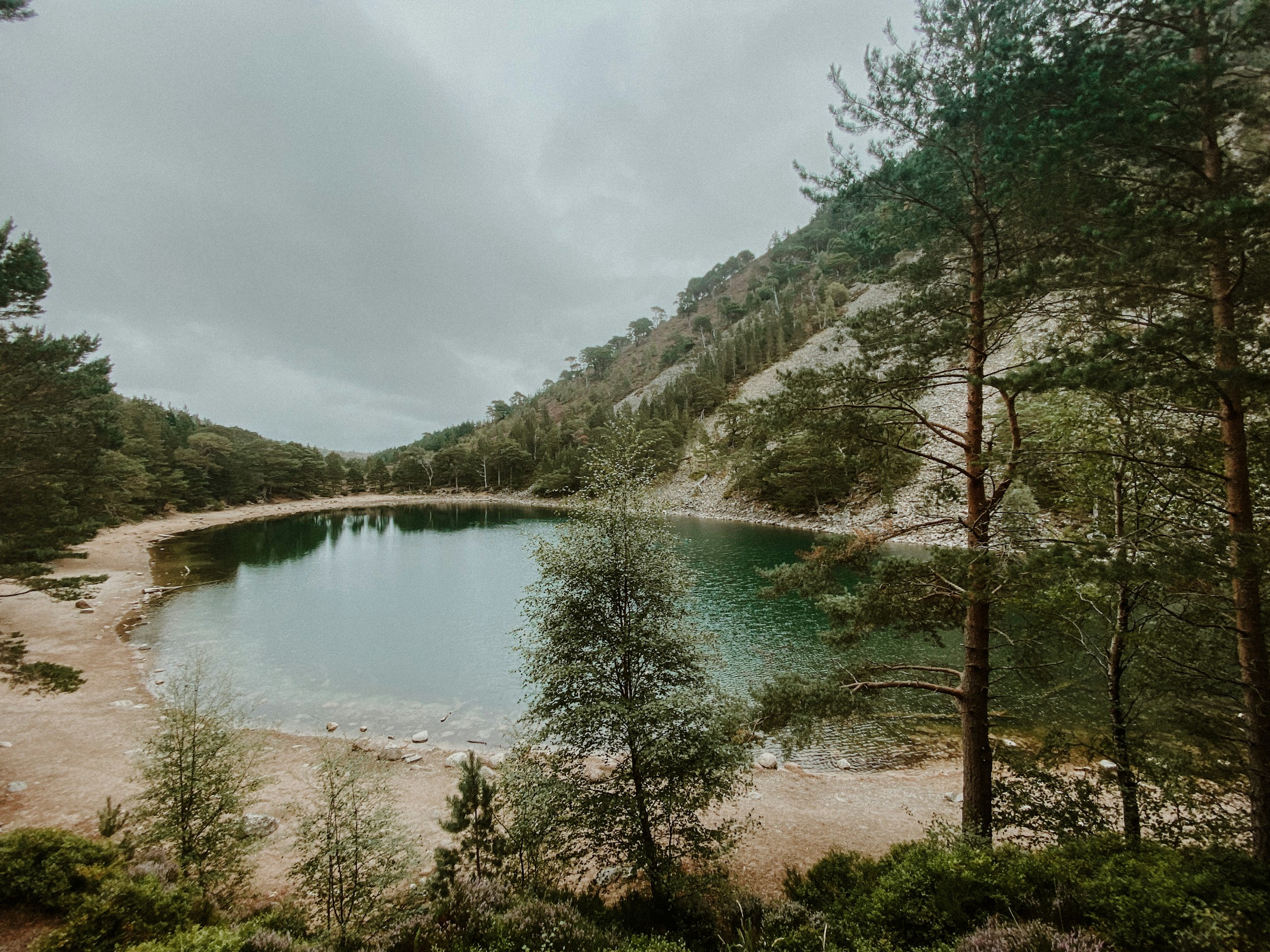 A still highland loch ringed by pine forest and rocky slopes near Aviemore in the Cairngorms.