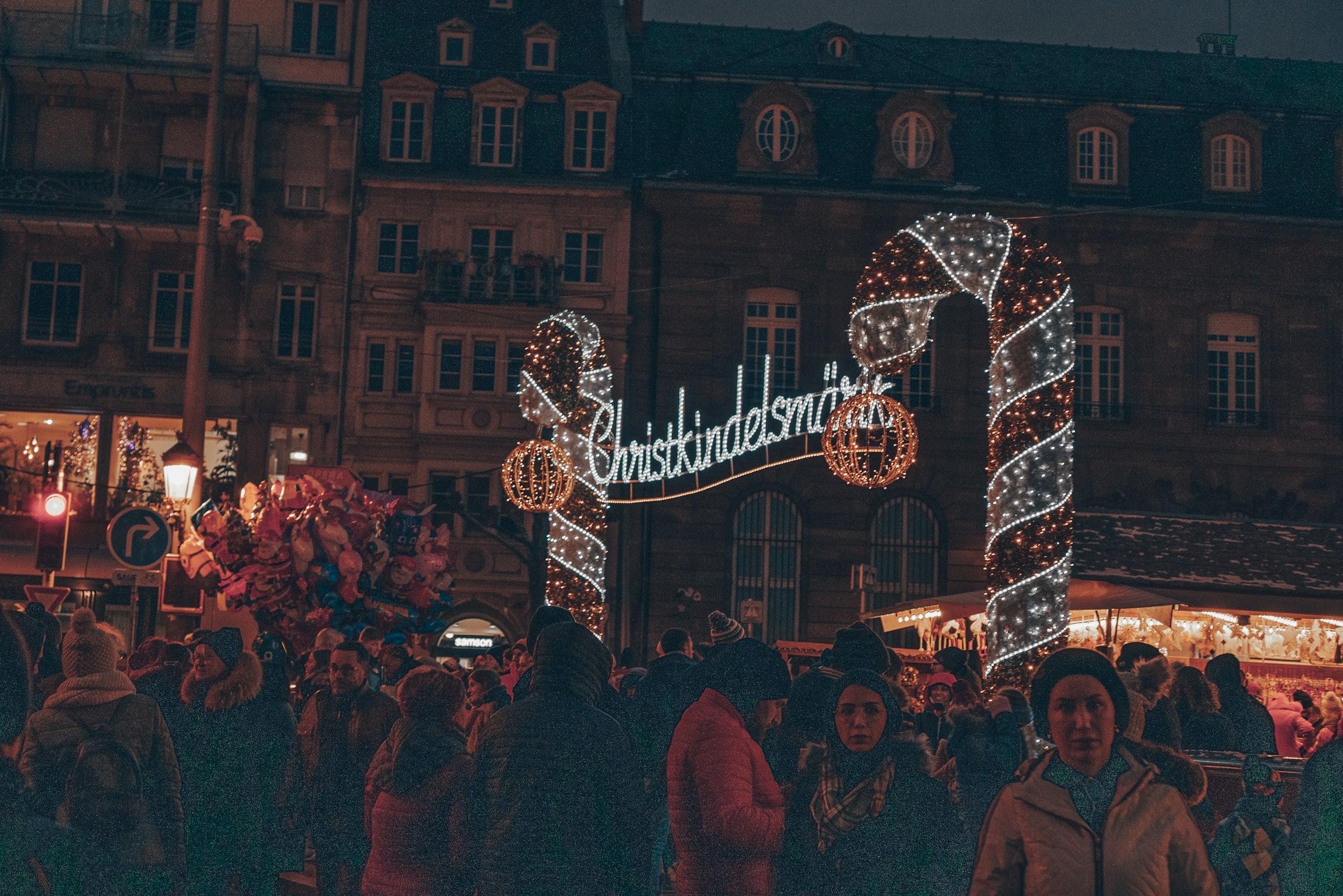 a crowd of people walking around a christmas market