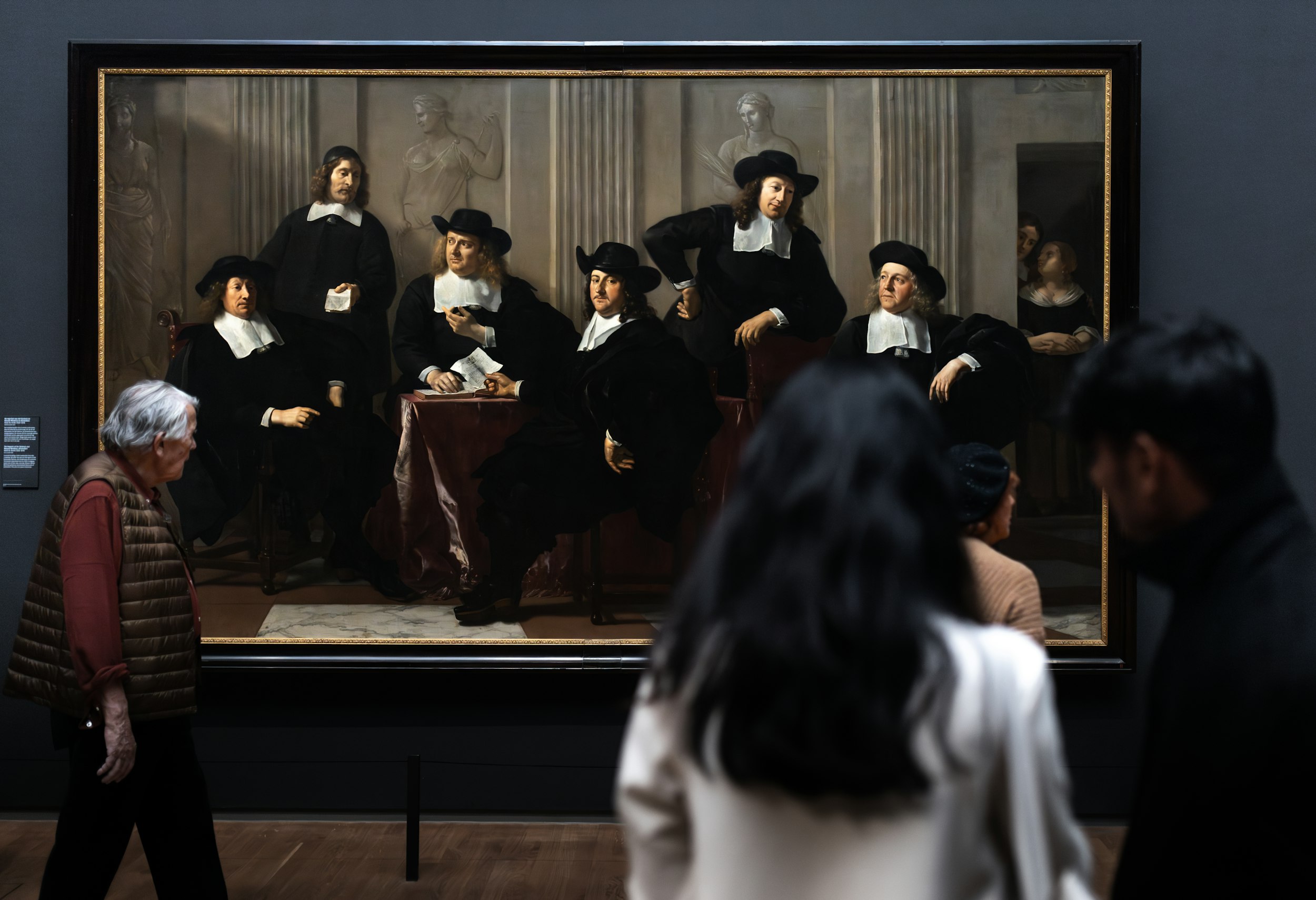 A view of people visiting the Rijksmuseum in Amsterdam by train, looking at an old painting.