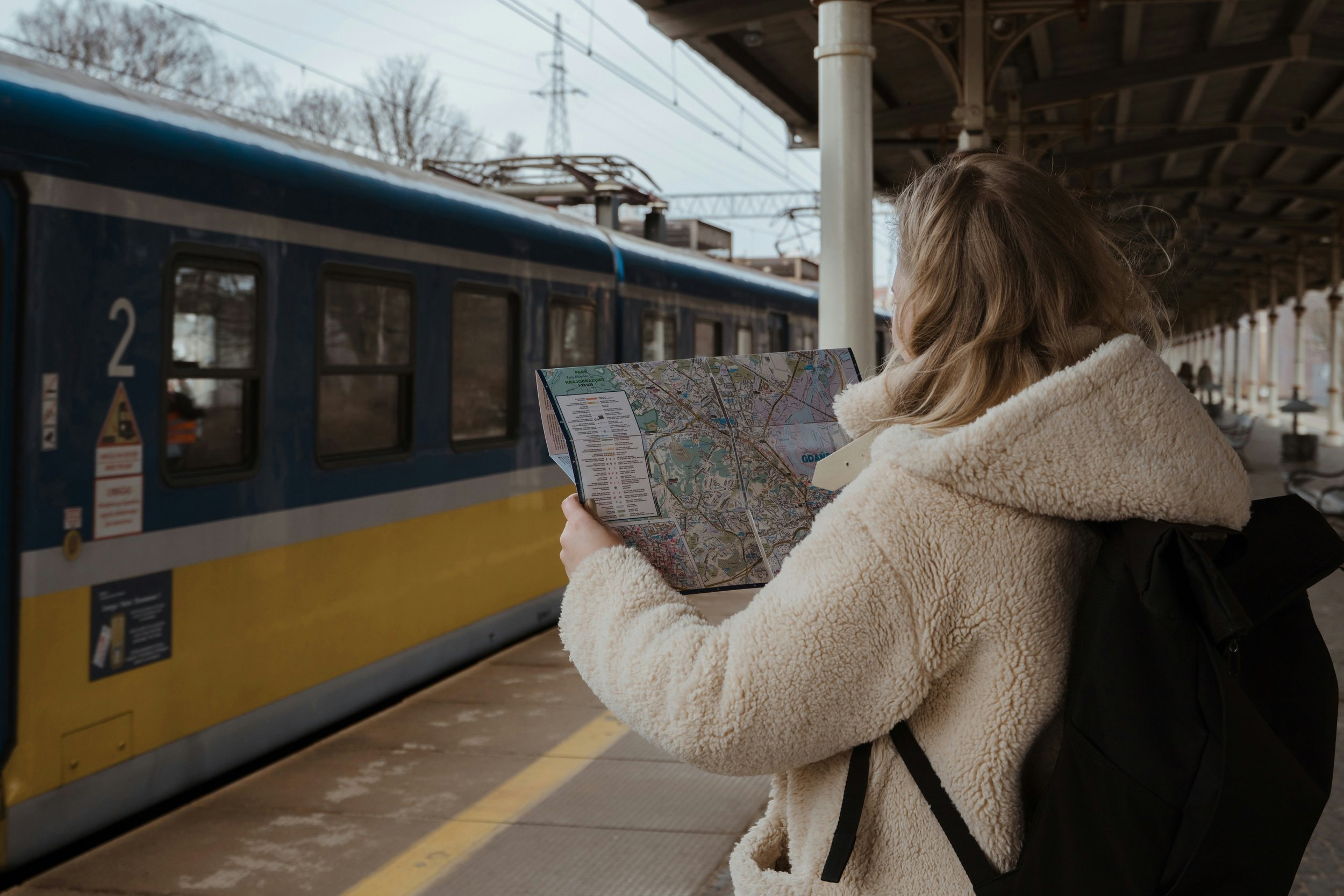 A woman reading a map in front of a train waiting at a station